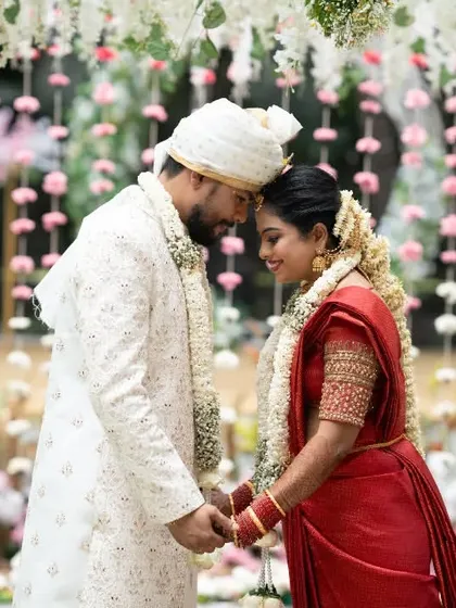 An intimate moment between the couple, their foreheads touching, surrounded by hanging floral decorations.