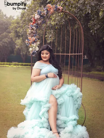 A whimsical solo portrait of the mom-to-be seated in a large, birdcage-style chair decorated with flowers. This unique prop adds a fairytale element to our outdoor shoots.