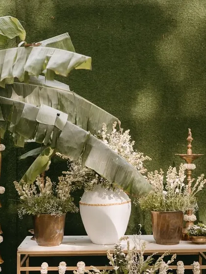 A close-up of the entrance decor, highlighting the use of natural elements like banana leaves and dried flowers, paired with traditional brass lamps for an earthy and elegant look.