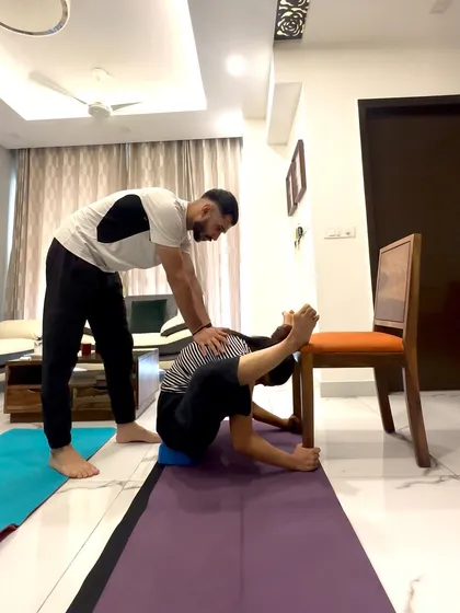 Here I am assisting a student in Dwi Pada Sirsasana (Two-Legs-Behind-Head Pose) using a block and chair for support. This shows how we break down complex poses into manageable steps.