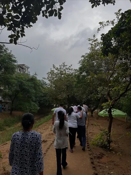Volunteers from Calpro Specialities walk along a path at the Aravali Creek site. The cloudy sky provides perfect conditions for a planting drive, helping the new saplings settle in.