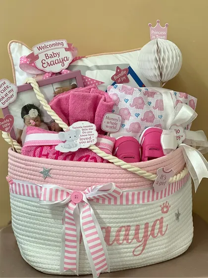 Pretty in pink for baby Eraaya! This personalized rope basket hamper is filled with essentials like onesies, towels, and shoes, all in a beautiful pink and white theme.
