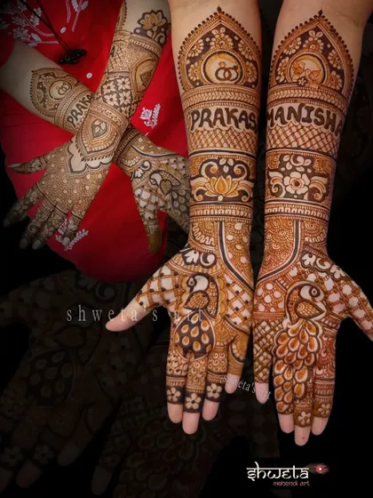 An engagement mehendi featuring the couple's names, Prakash and Manisha, prominently displayed. The design is complemented by beautiful peacock motifs on the palms.