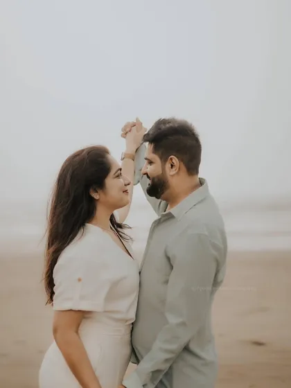 A gentle dance on the beach. This image captures a quiet, romantic moment between the couple, with their hands linked against the soft light of the coast.