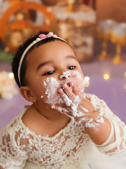This baby is fully enjoying her cake, a candid moment from a lace and pearls themed cake smash.