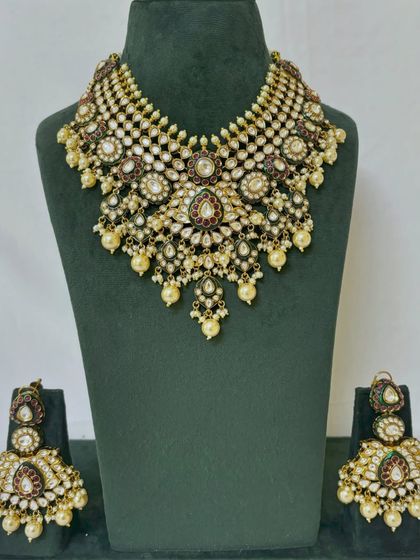 This rental choker set is adorned with small pearls and red and green stones. It comes with matching oversized earrings.