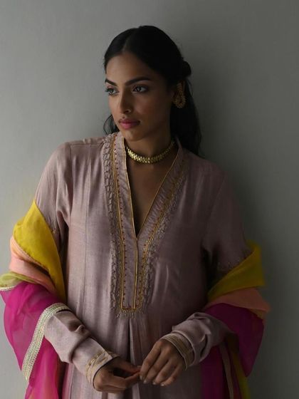 A model in a dusty pink kurta with a colorful striped dupatta, a beautiful blend of soft and vibrant hues.