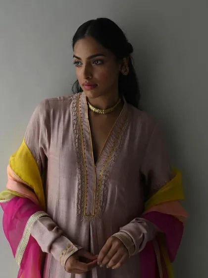 A model looking serene in a dusty pink kurta, accessorized with a multi-colored dupatta that adds a vibrant pop of color.
