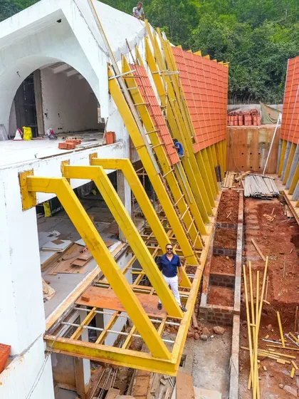 Here I am on-site during the construction of the Tellado Villas' roof. This image captures a critical moment in the building process, showcasing the scale of the yellow-painted steel framework that supports the iconic parabolic, tiled surface.