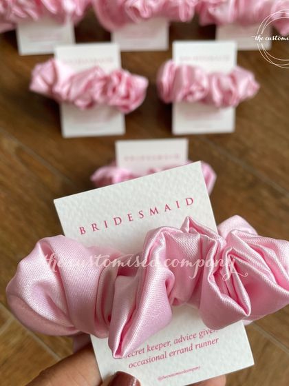 A small but sweet gesture for your bridesmaids. These pink satin scrunchies come with a personalized "Bridesmaid" card, making them a perfect addition to any proposal box or thank you gift.