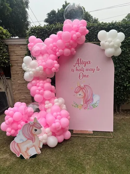 Celebrating a half-birthday is a growing trend, and we love creating decor for it. This "Half Way to One" setup features a cute unicorn theme with a pink backdrop and a whimsical pink and white balloon arrangement.