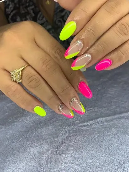Make a statement with vibrant neon colors. This design features a sharp, geometric color block with bright pink and electric yellow on almond-shaped nails, accented with a touch of glitter for extra pop.