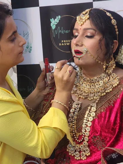 The final touches. Here I am applying lipstick to complete the bride's regal look, ensuring every detail is perfect.
