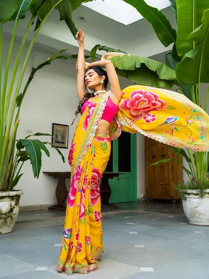 Capturing movement and color is my passion. In this outdoor shot, the model's dynamic pose makes the vibrant yellow floral saree come alive, showing the beautiful drape and flow of the fabric against a lush green background for a fresh, energetic lookbook image.