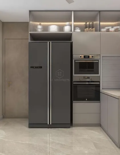 A view of the appliance wall in the 'Nivasa' kitchen. The integrated oven and microwave, along with the large refrigerator, are seamlessly built into the cabinetry for a clean, uncluttered look.