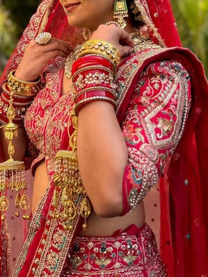 A detailed shot of the sleeve and side profile of a traditional red bridal lehenga. The heavy embroidery and rich fabric are hallmarks of our premium bridal rental collection.