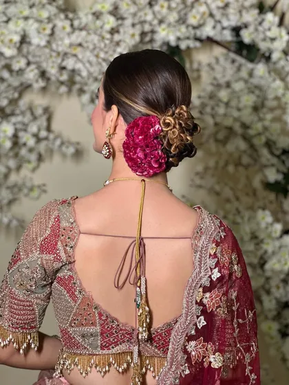 A beautiful knotted bridal bun. The texture and shape of this updo are modern and chic, and the addition of the fresh flower adds a touch of classic romance.