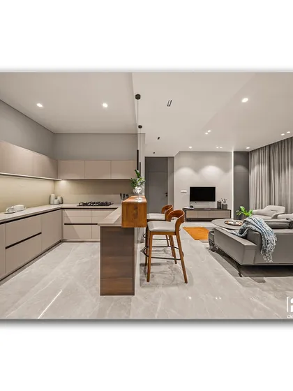 An open-concept living space that exemplifies warm minimalism. The clean lines of the kitchen, the simple bar seating, and the comfortable grey sofa create a cohesive and uncluttered environment that is both stylish and functional.