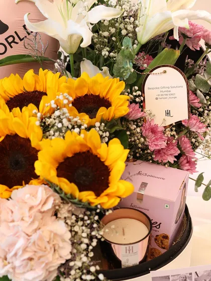 A detailed view of the treats included in the sunflower hamper. You can see the Le15 macaron box and the custom-branded scented candle, showing the quality of the curated items.