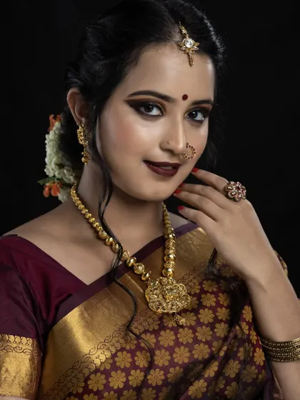 This studio portrait showcases a bold and defined bridal look. The sharp winged eyeliner, deep maroon lip, and perfectly sculpted features are ideal for brides wanting a high-impact, photogenic style for their wedding day.