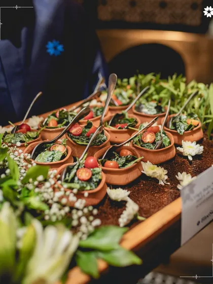 Small terracotta pots filled with a fresh, vibrant salad. This presentation adds a rustic, earthy charm to the dish and is perfect for an outdoor or garden themed event.