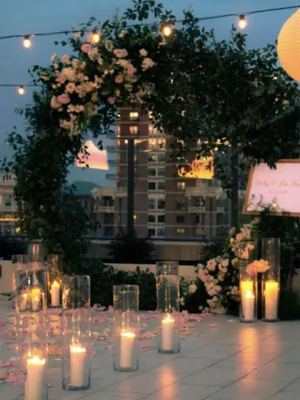 A beautiful floral arch set against the twilight sky. This elegant decor, surrounded by pillar candles, is perfect for a proposal or a very intimate wedding vow exchange.