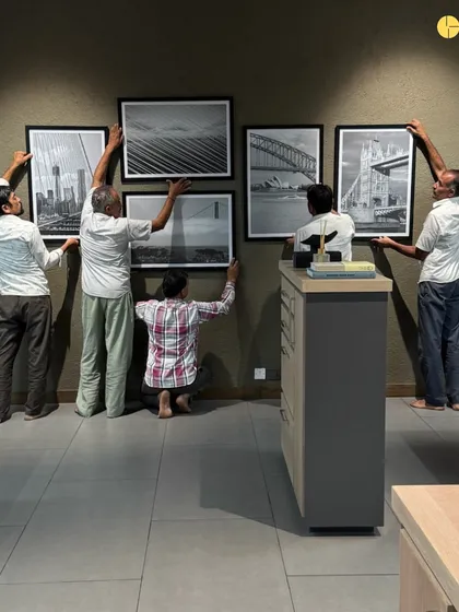 A team of craftsmen working together to install a gallery wall in a corporate office. This image captures the precision and teamwork required to execute the final details of an interior design project.