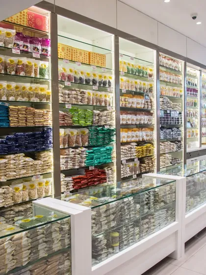 A view of the shelves and counters inside my shop. You can see the wide range of products, from packed dry fruits on the top shelves to fresh snacks in the glass counters below. It's all organized for your convenience.