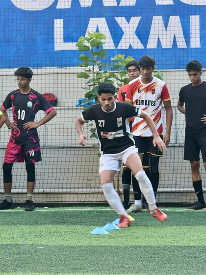 A young footballer navigates a cone drill during the Delhi Youth League trials. These drills are designed to test and improve a player's agility, ball control, and speed.