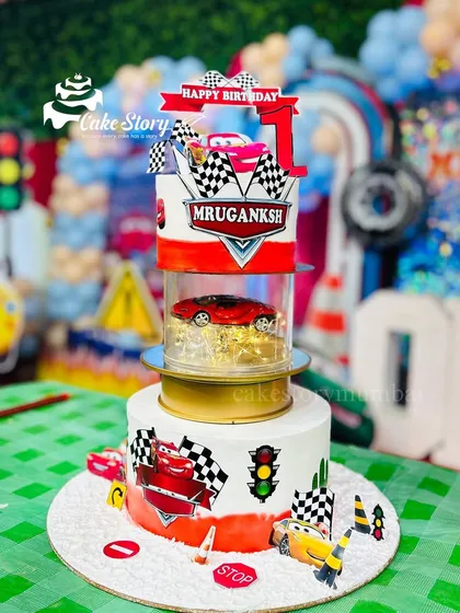 Bringing the excitement of the race track to a first birthday party with this rotating car-themed cake. It features characters from the movie 'Cars', traffic signals, and a real spinning tier that makes it a showstopper for any little car enthusiast.