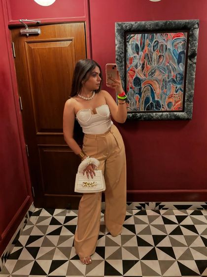A late-night fashion post featuring a white corset top and beige wide-leg trousers. A classic and elegant combination.