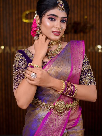 A stunning purple and gold Kanchipuram saree. The draping style is grand and traditional, perfect for a classic bridal photoshoot.