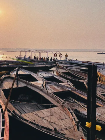 boats gathered on the ganges at sunset. the warm, soft light and composition create a feeling of tranquility.