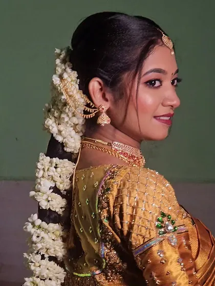 A classic muhurtham look for a temple wedding. The bride's gold saree and traditional hairstyle with jasmine flowers are simply timeless.