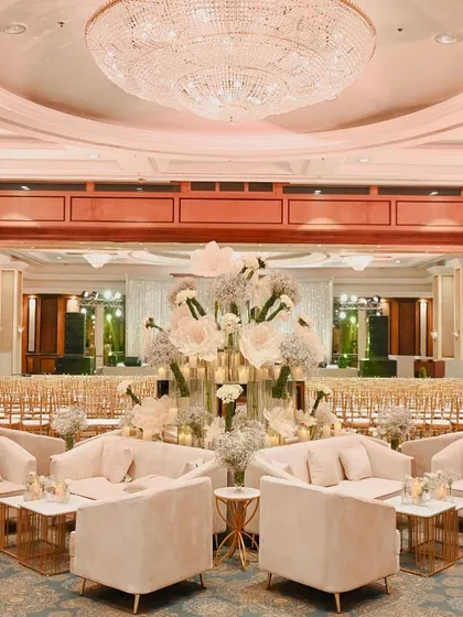 The central lounge area of the ballroom, featuring a massive floral installation and plush seating, all under a grand crystal chandelier.