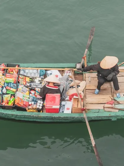 A top-down view of a floating shop in Halong Bay, its small boat filled with a variety of snacks and drinks for sale.