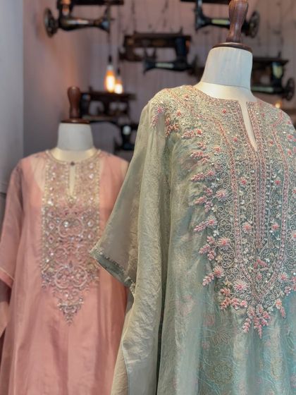 Pastel perfection meets intricate embroidery. A close-up of two kaftans in soft pink and sage green, featuring delicate floral beadwork.