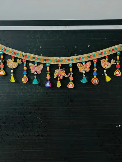 The 'Bageecha Toran' displayed against a dark wall, making the colors of the birds, butterflies, and elephants truly pop.