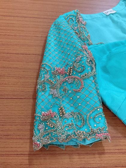 A duplicate image showing the detailed sleeve embroidery on the turquoise blouse.