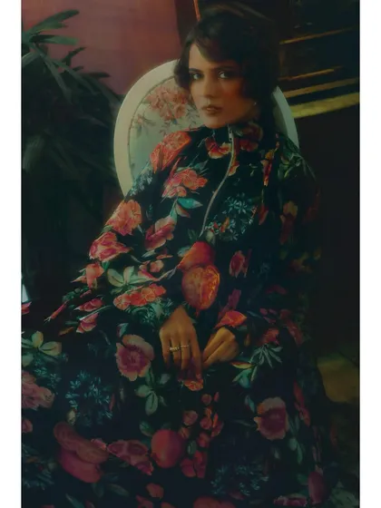 Another portrait from the first chapter, focusing on the details of the styling. The high-collared floral dress and the model's pose convey a sense of quiet introspection.