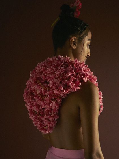 A conceptual beauty and fashion shot where a garment is made entirely of pink carnations. This styling choice transforms a natural element into wearable art, creating a unique and visually arresting image.
