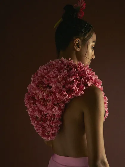 A conceptual beauty and fashion shot where a garment is made entirely of pink carnations. This styling choice transforms a natural element into wearable art, creating a unique and visually arresting image.