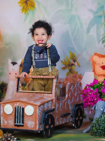 This little explorer is ready for his jungle safari, dressed in suspenders and posing with his jeep and animal friends.
