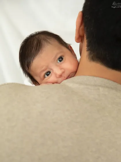 A newborn peeking over dad's shoulder. This shot perfectly captures the feeling of safety and curiosity in those early days.