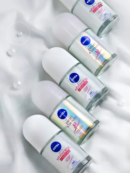 A clean, high-key flat lay of Nivea roll-on deodorants on a silky white fabric. This type of shot is perfect for e-commerce, showcasing product variety in a crisp and appealing way.