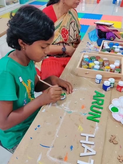 Painting the letters is a key step! Here a child is carefully painting the wooden letters for her custom nameplate.