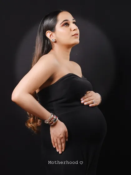 This solo maternity portrait uses focused lighting to create a hopeful and contemplative mood. The mom-to-be's pose gently cradling her bump is a classic expression of motherhood.
