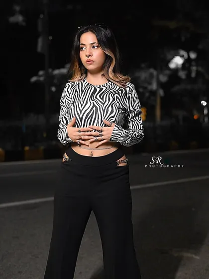 A street style shot at night with a zebra-print top. The selective color effect makes the model pop against the monochrome background.