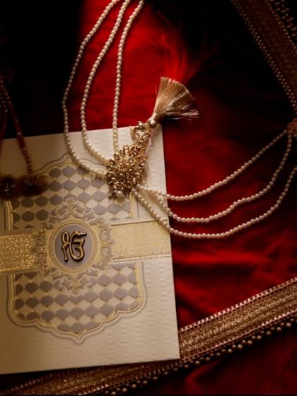 A detailed shot of a beautiful Sikh wedding invitation card featuring the 'Ek Onkar' symbol. This photo captures the cultural and personal touches that begin the wedding journey.