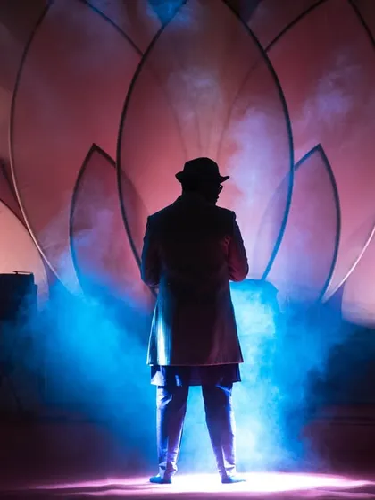 A performer silhouetted against the stage lights, creating a dramatic and mysterious image.